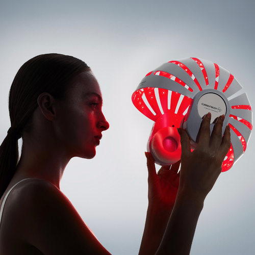 Woman holding the CurrentBody LED red light helmet for scalp health