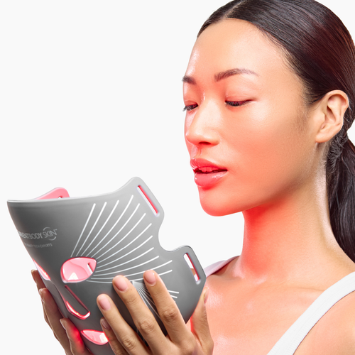 Model holding the CurrentBody Skin LED Multi-Light Mask to face